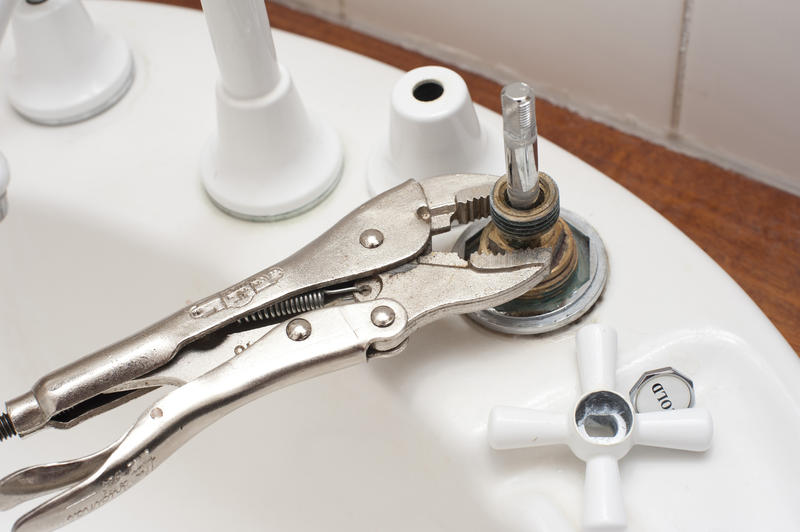 Fixing a plumbing installation in a bathroom with a mole grip wrench being used to secure and replace a washer