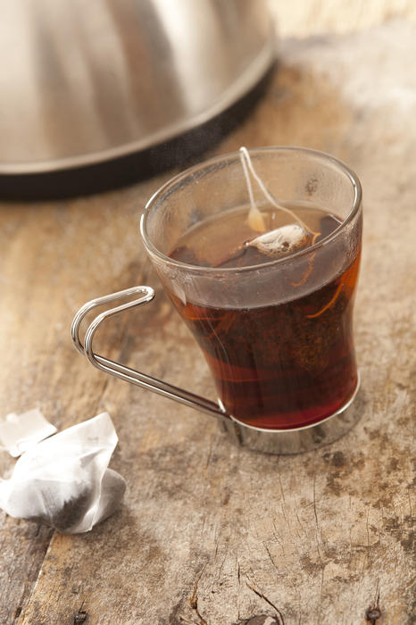 Hot cup of delicious fresh tea brewing in a rustic kitchen with a tea bag steeping in a glass mug of boiling water