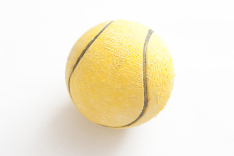 Close up of a single yellow tennis ball on a white background in a sport and exercise concept