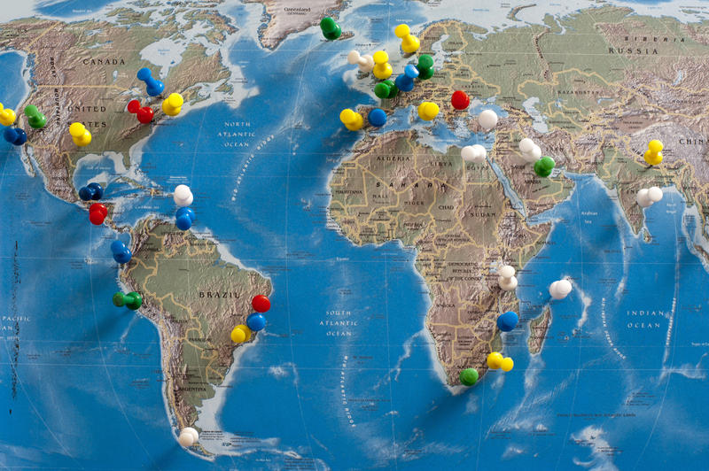 Multi-Colored Thumb Tacks Inserted in Various Locations on Wall Map of the World