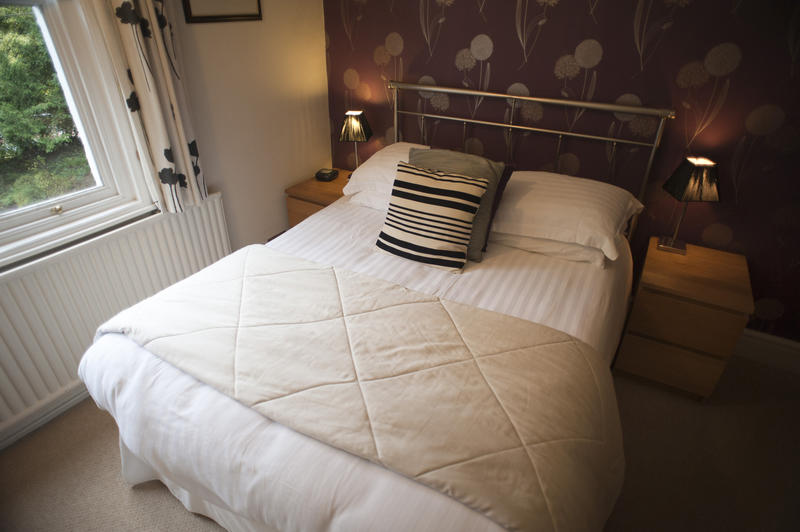 Trendy bedroom with neutral decor and a quilted throw on a comfortable double bed with striped cushions