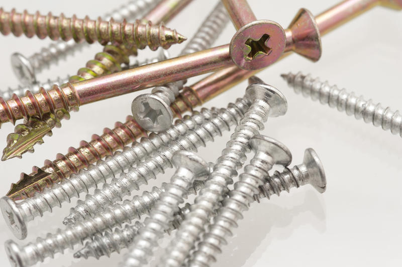 Variety of screws with fully threaded and countersunk examples in a haphazard pile on a white background in a DIY and renovation concept