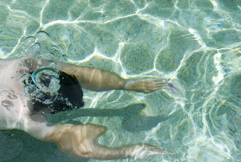 One Fit Male Swimmer Swimming Under Clear Sea Water on a Tropical Climate.