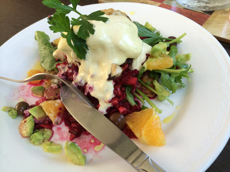 Warm fish salad with a grilled fish fillet topped with a creamy sauce on a bed of leafy green mixed salad garnished with parsley