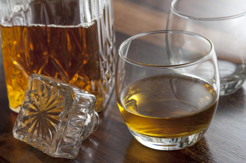 A whiskey glass and decanter stopper on a wooden table