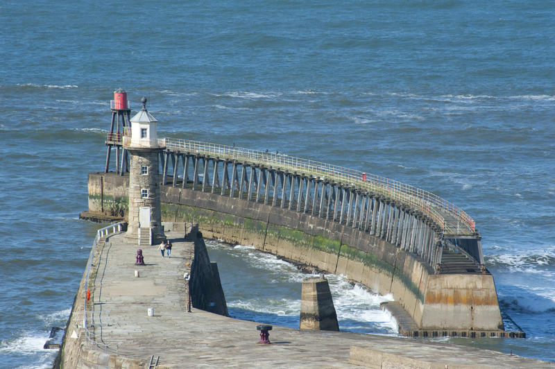Whitby East Pier with its stone navigation lighthouse and curving breakwater at the entrance to Whitby harbour on the Yorkshire coast