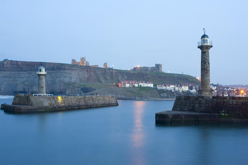 Breakwater navigation beacons with look over the seaside village at dusk