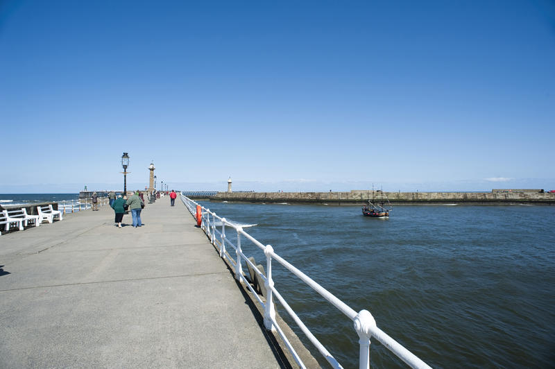 People walking along the promenade on top of the West Pier, Whitby