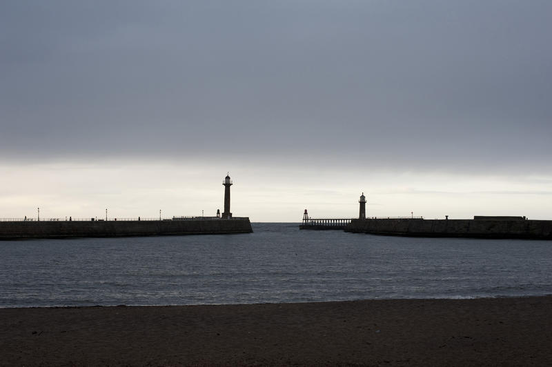 Navigation lights on stone piers and breakwaters at the entrance to Whitby harbour on the Yorkshire coast at dusk