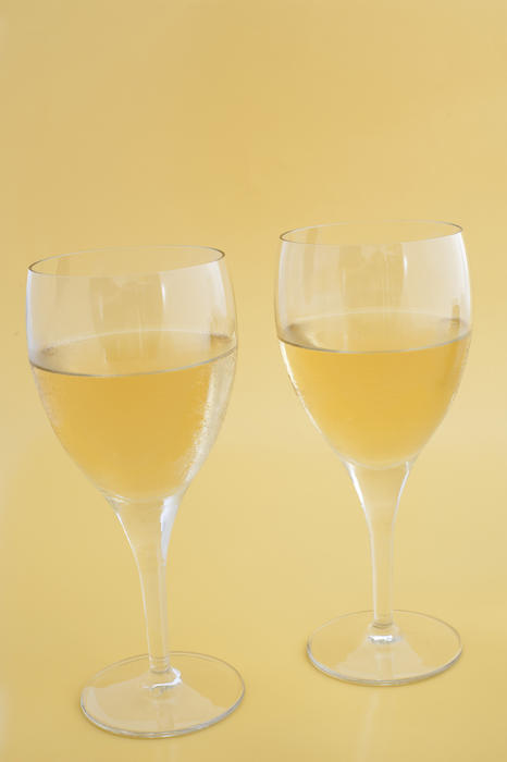 Two glasses of white wine ready for celebration, close-up on yellow