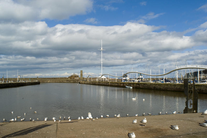 Inner basin at the Whitehaven harbour with seagulls perched on the quay and leisure boats visible moored in an adjacent marina