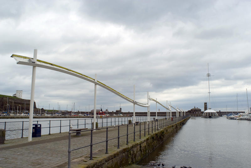 View along the deserted seawall and promenade at Whitehaven harbour on a grey cloudy day