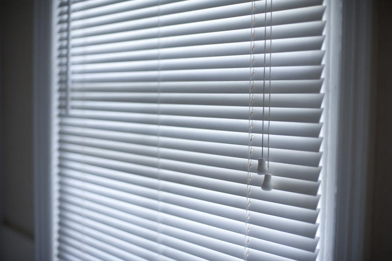 Angled view of Venetian blinds hanging in a window with the slats raised to reduce sunlight or provide privacy