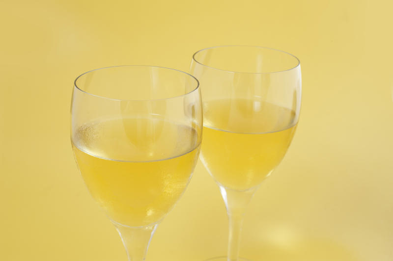 Two glasses of wine wine on a pale yellow background as an aperitif or accompaniment to a meal