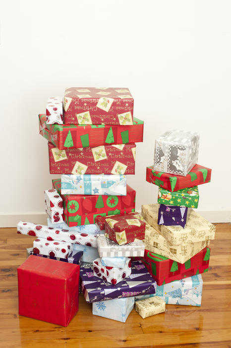 Pile of gift boxes wrapped in paper with colorful Christmas patterns, on the floor