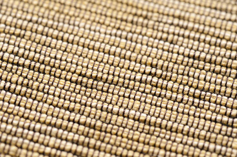 Yellow fabric background texture with a close up view of the coarse weave and fibers with center focus