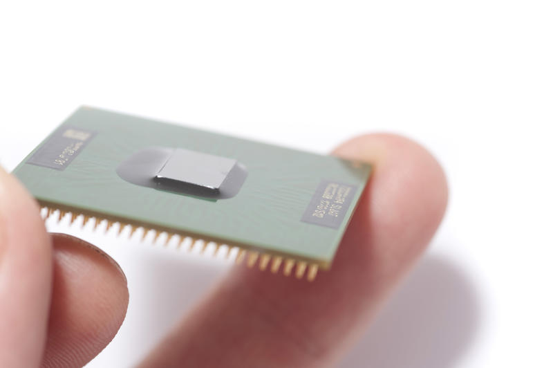 Close-up image of man holding CPU chip in fingers against white background