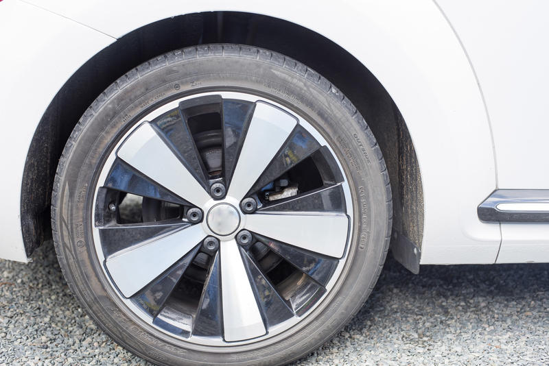 Alloy wheel with spokes on a modern white sedan car parked on an asphalt road in a close up view