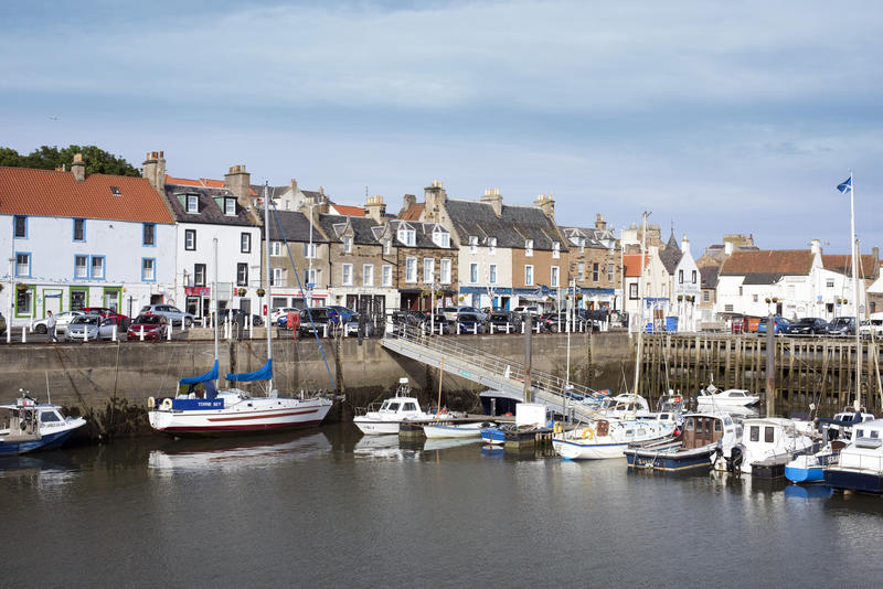 View from across the water of various docked boats at pier in Anstruther, Scotland