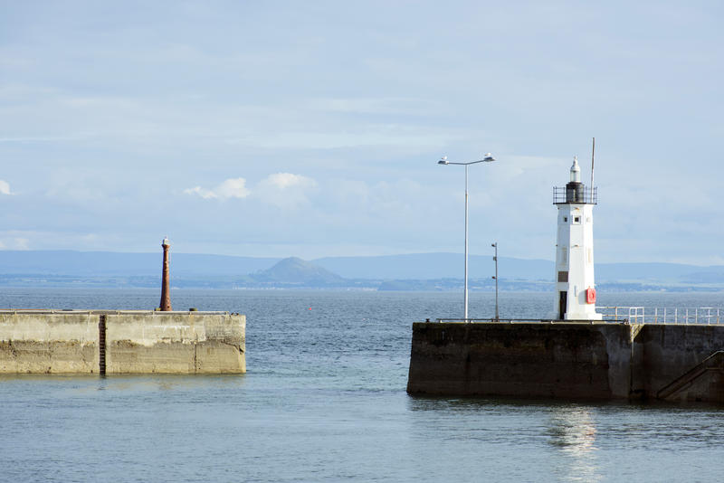 Navigation beacon and small lighthouse on the harbour entrance at Anstruther, Scotland with a calm ocean