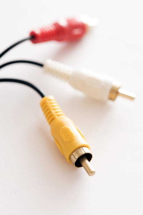 Cable with RCA plugs, yellow for composite video and white and red connectors for stereo audio selective focus image on white background