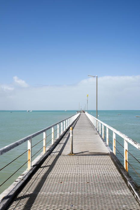 View along the deserted jetty at Beachport, Australia stretching away into the ocean on a sunny blue sky day