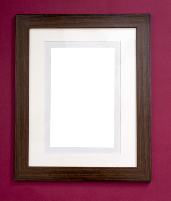 Plain blank wooden picture frame with a black stained border and central white copy space hanging on a burgundy colored wall