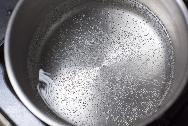 Clean boiling water in a stainless steel pot heating on a stove or hotplate viewed from overhead