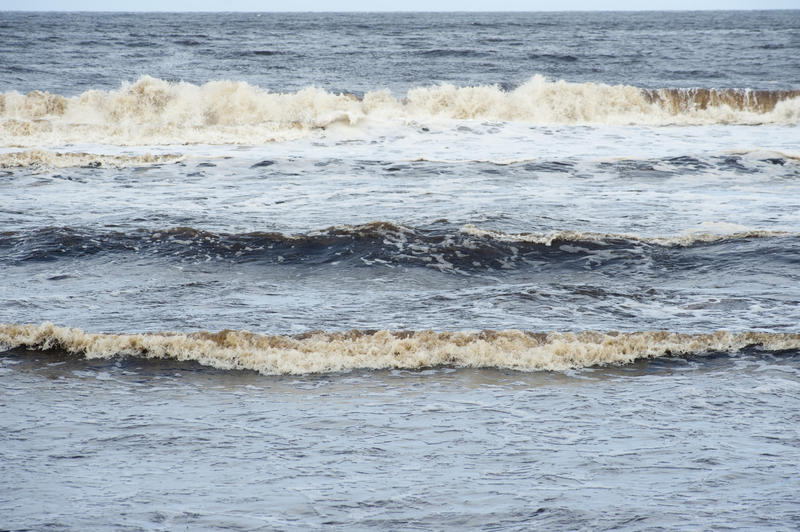 Breaking waves at the edge of the ocean rolling in towards the shoreline with the ebb and flow of the tides, full frame background