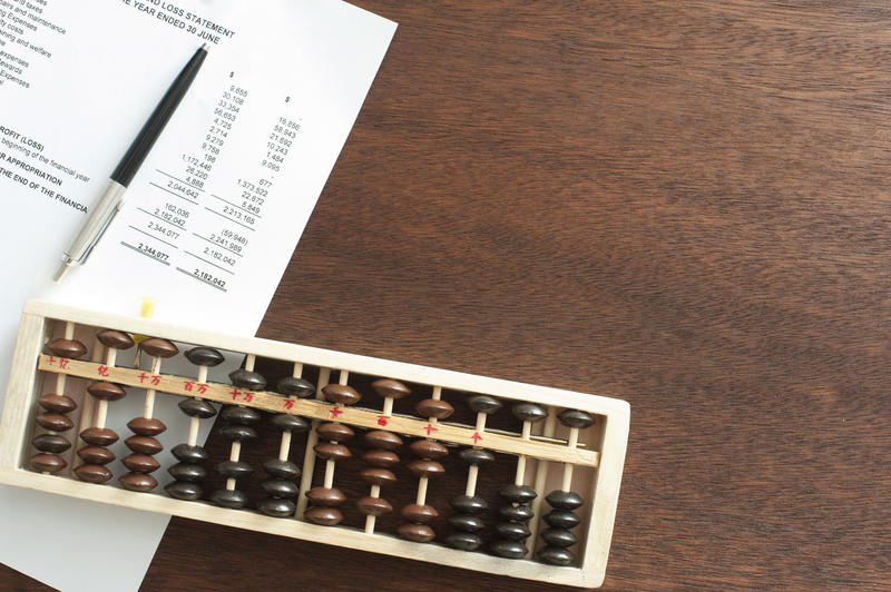 Business finance concept with abacus and statement over dark wooden table with copy space in top corner