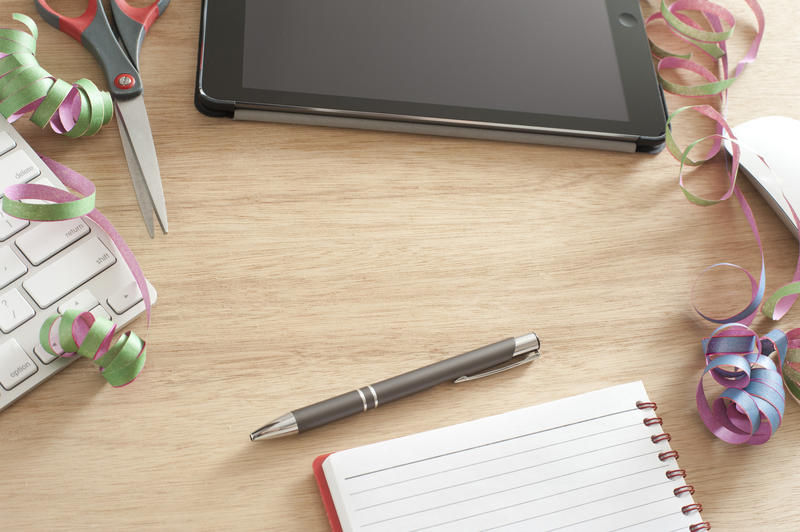 High Angle Still Life of Office Supplies on Desk with Copy Space - Curled Ribbons Strewn on Wooden Computer Desk with Tablet, Notebook and Pen