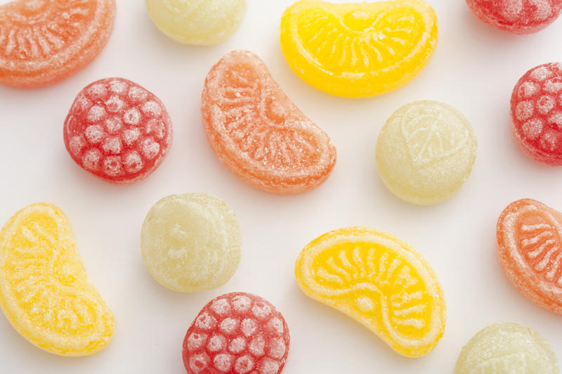 Fruit shaped boiled sweets or candy background in assorted shapes and flavors scattered on a white surface