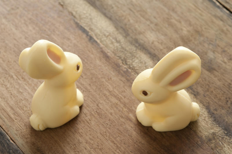 Two little white milky bunny Easter Eggs on a wooden table viewed high angle with copy space and focus to their large ears