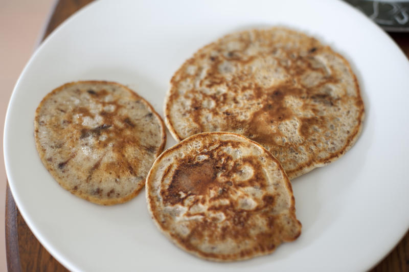 Three homemade fried chocolate chip pancakes served on a white plate in a high angle view