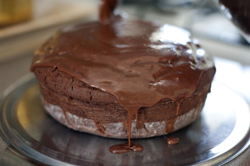 Delicious freshly baked chocolate sponge cake topped with chocolate icing standing cooling in a kitchen in a close up view