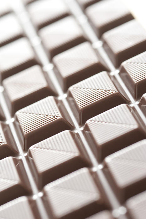 Selective focus angled view on delicious milk chocolate squares with little diagonal lines etched into them