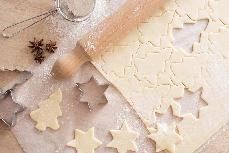 Close up shot of sheet of dough with pieces in shape of cookies being cut from it