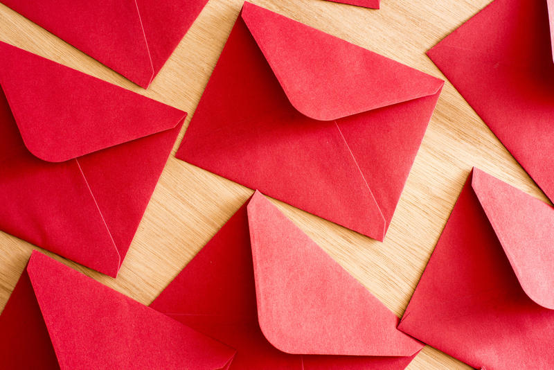 Bright colorful red Christmas envelopes on a wood background for your festive correspondence to a loved one or friend, overhead full frame view