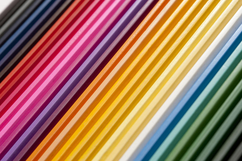 Close up view on tight row of blue, red, purple, orange, yellow and green hues of colored pencils