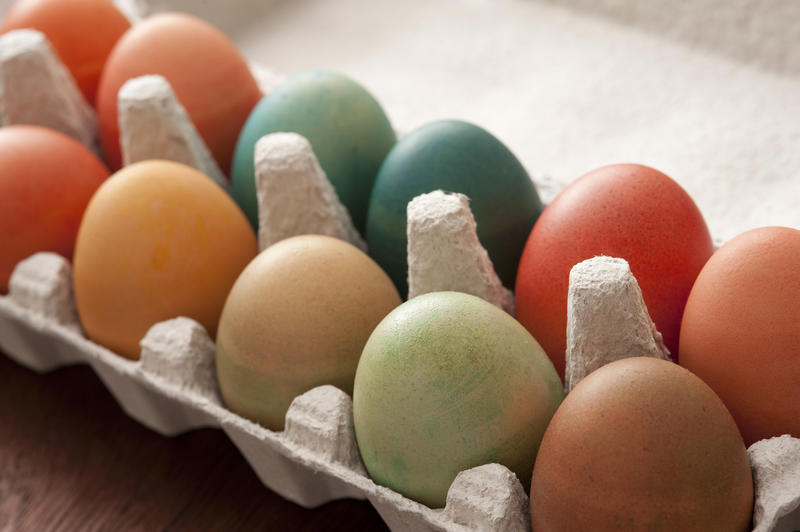 Close up view of opened paper egg box with colorful dyed Easter eggs on wooden table