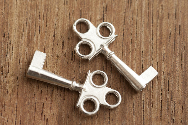 Two short silver keys with single flat end and three holes at their handles