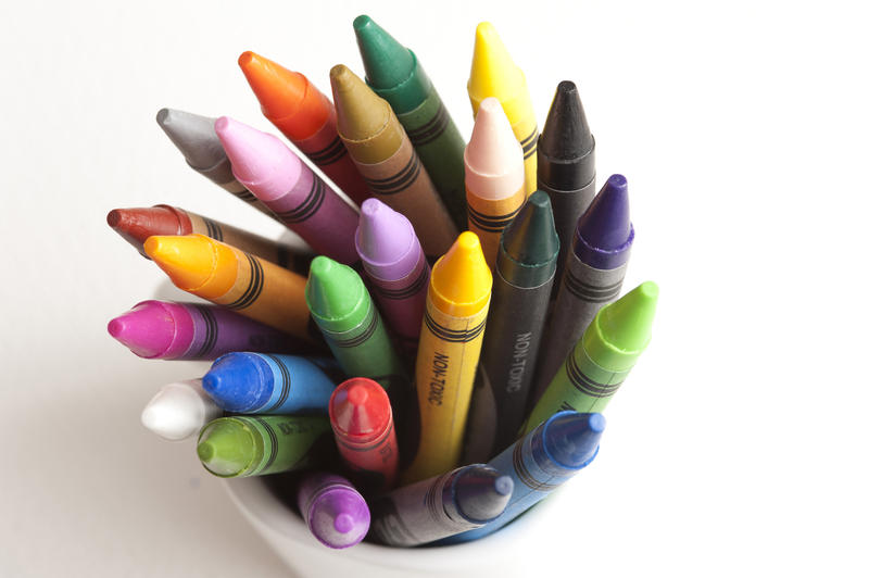 Close top down view of assorted loosely packed bright and dark crayon tips in cup