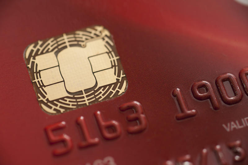 Detail of the reflective metallic microchip on a red credit card with partial numbers visible