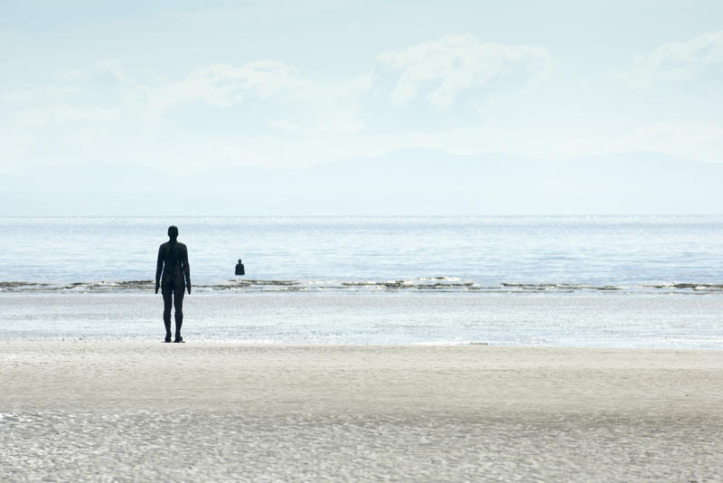 Cast Iron Man Figures Facing Sea as part of Another Place Modern Sculpture Installation by Antony Gormley, Crosby Beach, England, UK