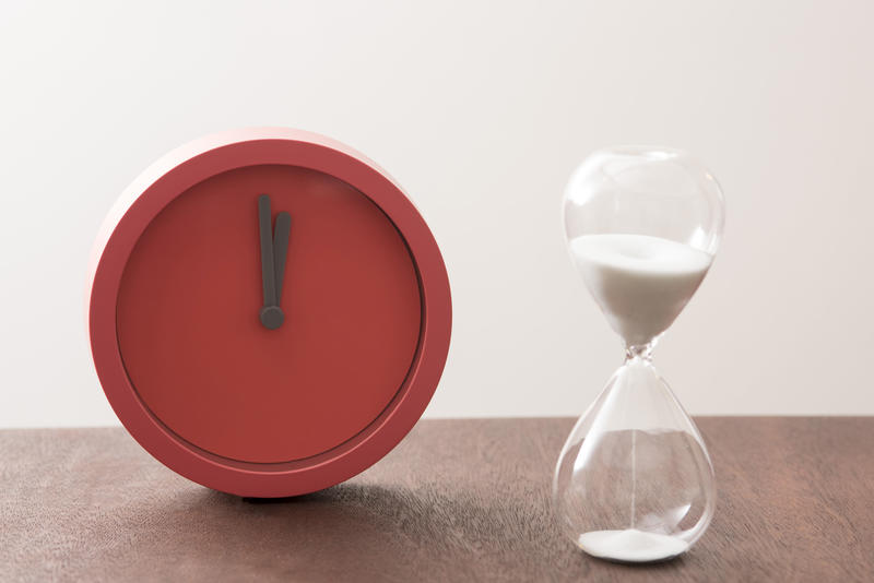 Modern red timer clock and egg timer with running sand in a concept of passing time and countdown to a deadline