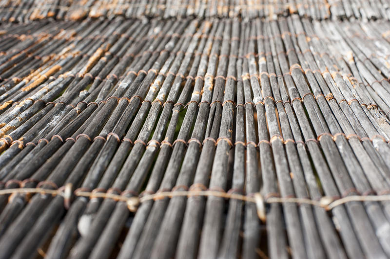 Close up low angle view on cane floor mat with strings holding it together and pattern of converging lines and selective focus