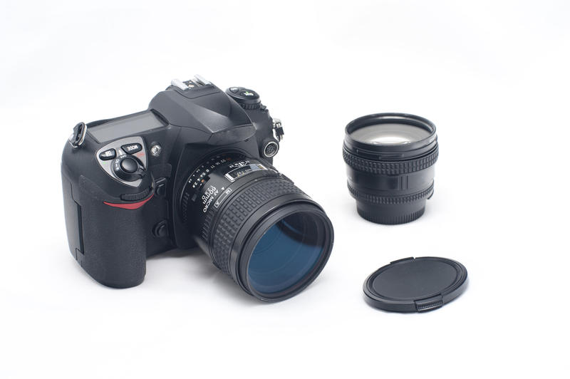 Still Life of Modern Digital SLR Camera with Zoom Lens and Lens Cap Nearby on White Background - Film and Photography Concept Image