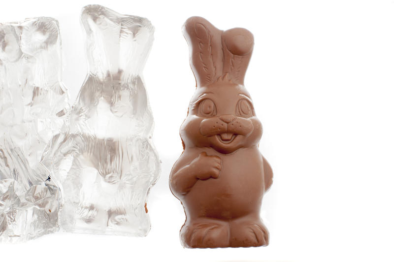 Fat little chocolate Easter bunny with its opened empty foil wrapper retaining the shape alongside isolated on white with copy space