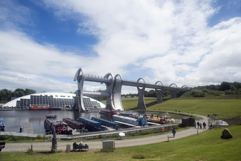 Wide angle view of path, docked small ships and people near harbor at Falkirk Wheel boat lift in Scotland