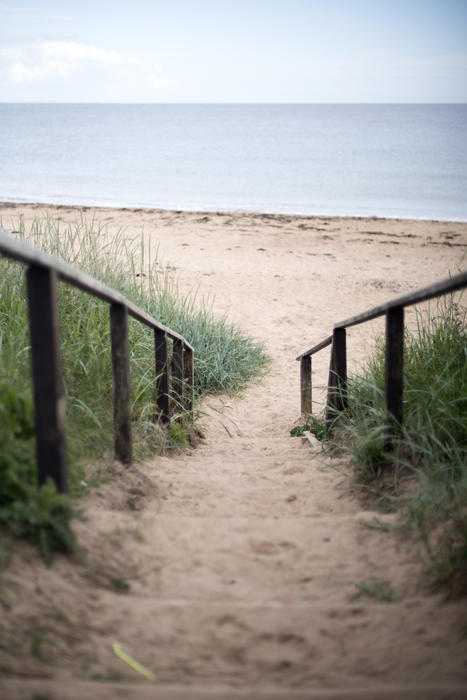 First person perspective view downward on sand covered stairs at spacious beach in Fife Coast, Scotland